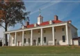 A historic building with a red roof and large white columns under a clear blue sky.