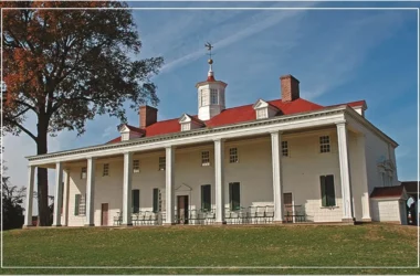 A historic building with a red roof and large white columns under a clear blue sky.