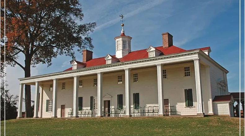 A historic building with a red roof and large white columns under a clear blue sky.
