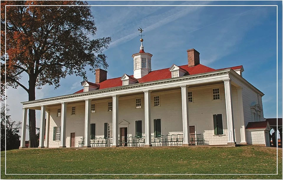 A historic building with a red roof and large white columns under a clear blue sky.
