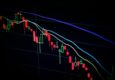 Close-up of a stock market candlestick chart displaying fluctuating prices in various colors against a dark background.