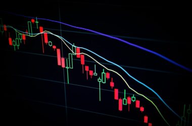 Close-up of a stock market candlestick chart displaying fluctuating prices in various colors against a dark background.