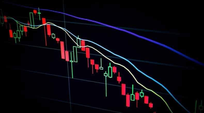 Close-up of a stock market candlestick chart displaying fluctuating prices in various colors against a dark background.